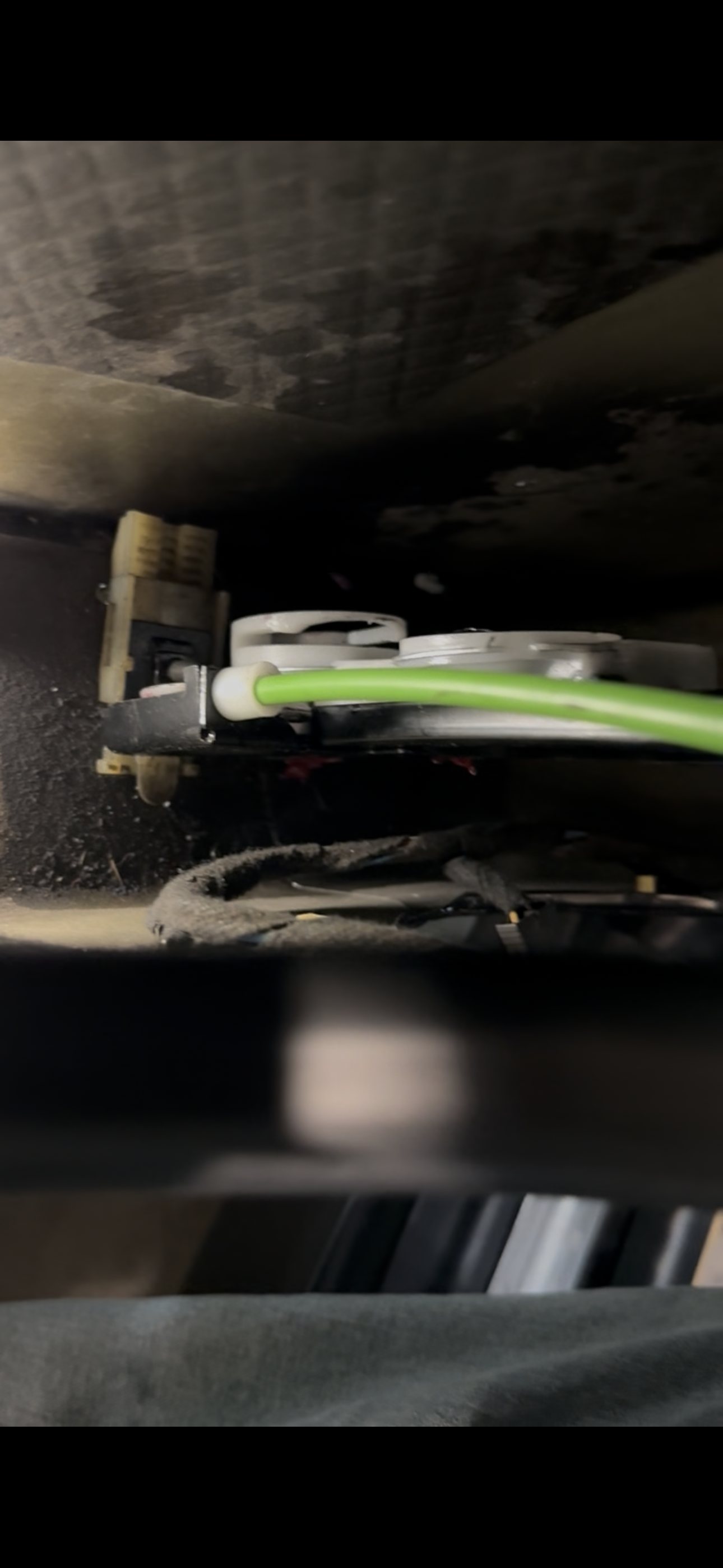 Green replacement window regulator cable seated in a white guide inside the driver door