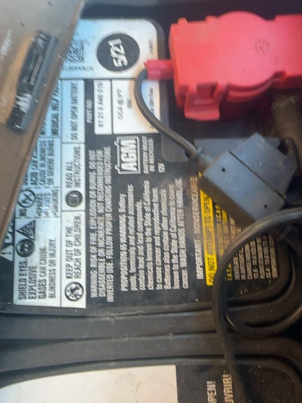 Top label of the BMW Group AGM battery showing a 5/21 date marking next to the red positive terminal cover