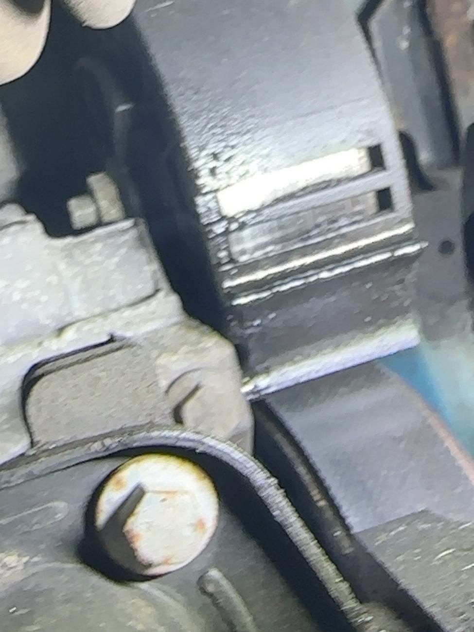 Close-up of the accessory-drive area at the front of the engine with a damp-looking surface