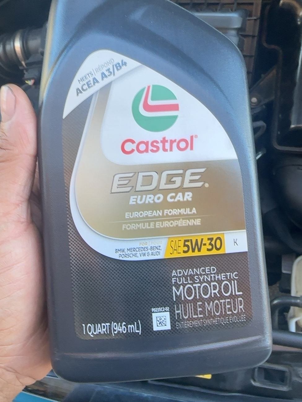 Hand holding a one-quart bottle of Castrol EDGE Euro Car 5W-30 in the engine bay