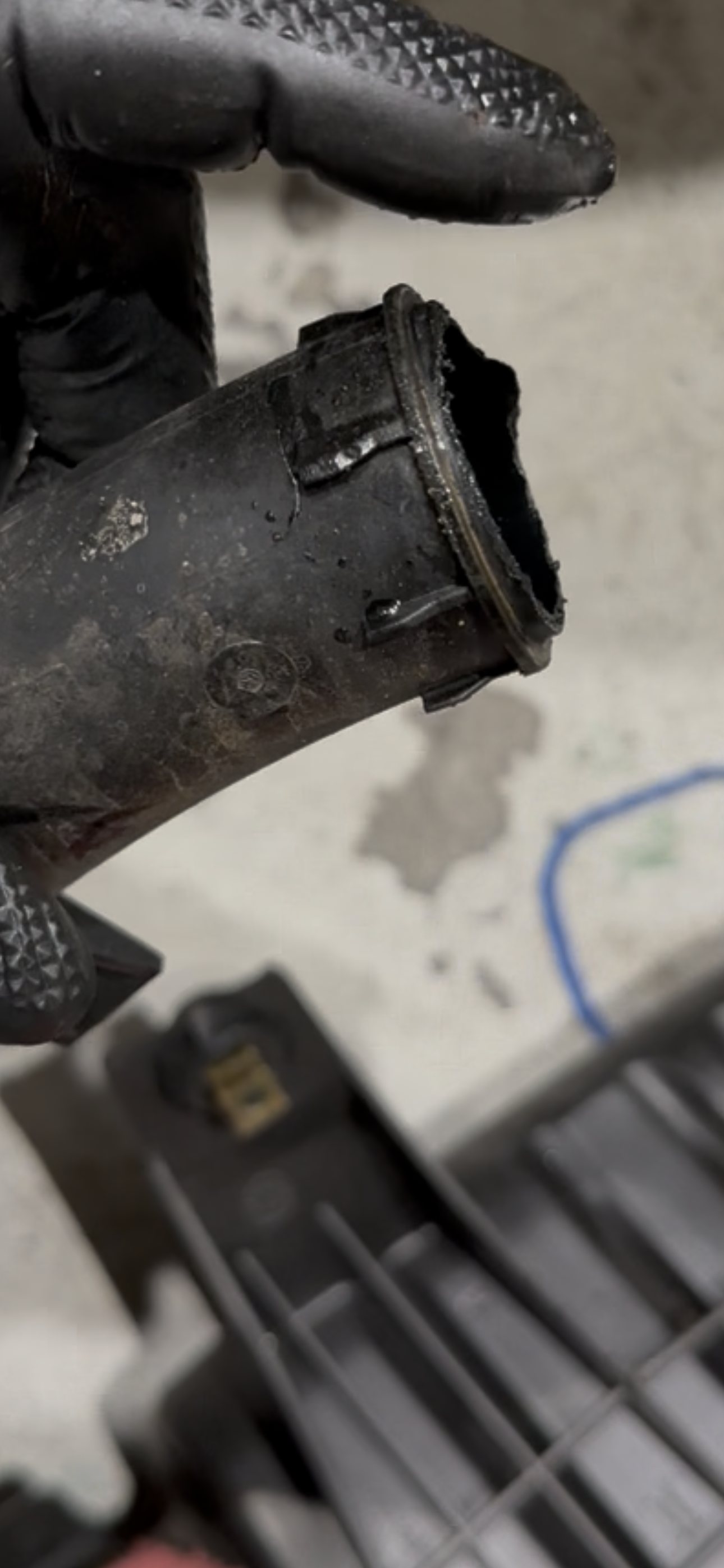 Angled close-up of the deteriorated crossover pipe rim, with crumbled plastic and residue around the sealing face
