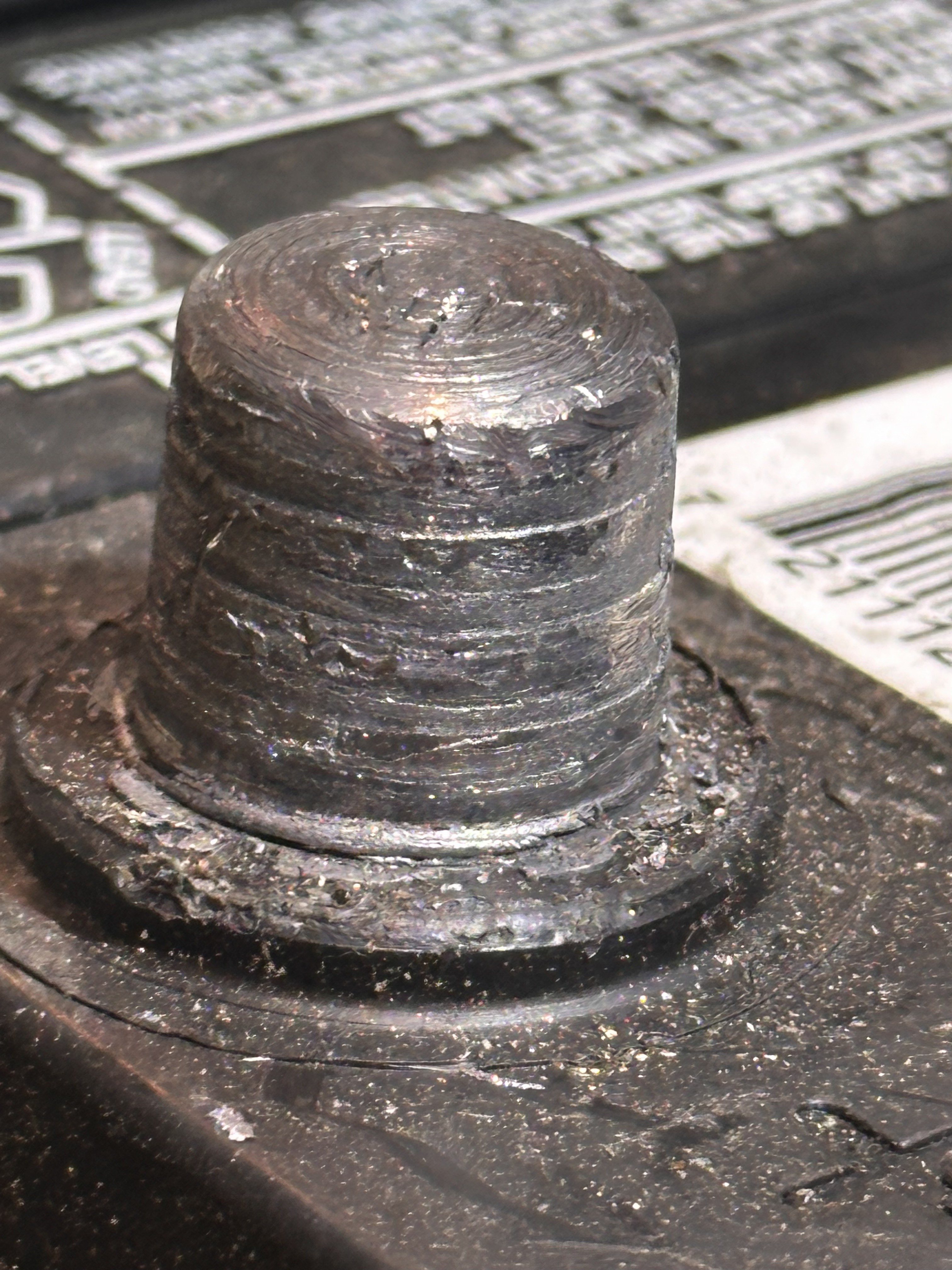 Close-up of the same battery post before cleaning, showing ridges and pits on the contact surface and debris on the ledge at its base.