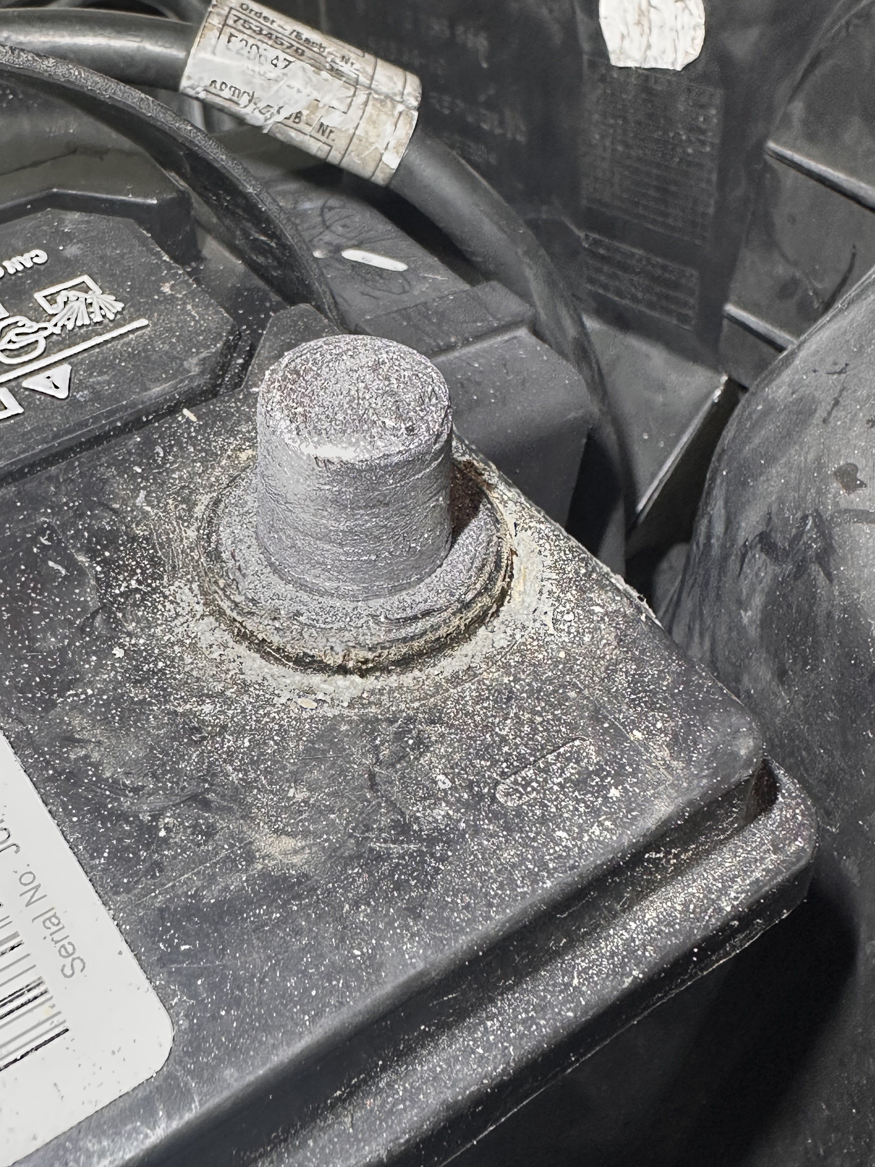 Battery post after cleaning, with an even matte grey lead surface and residue on the battery case around its base.