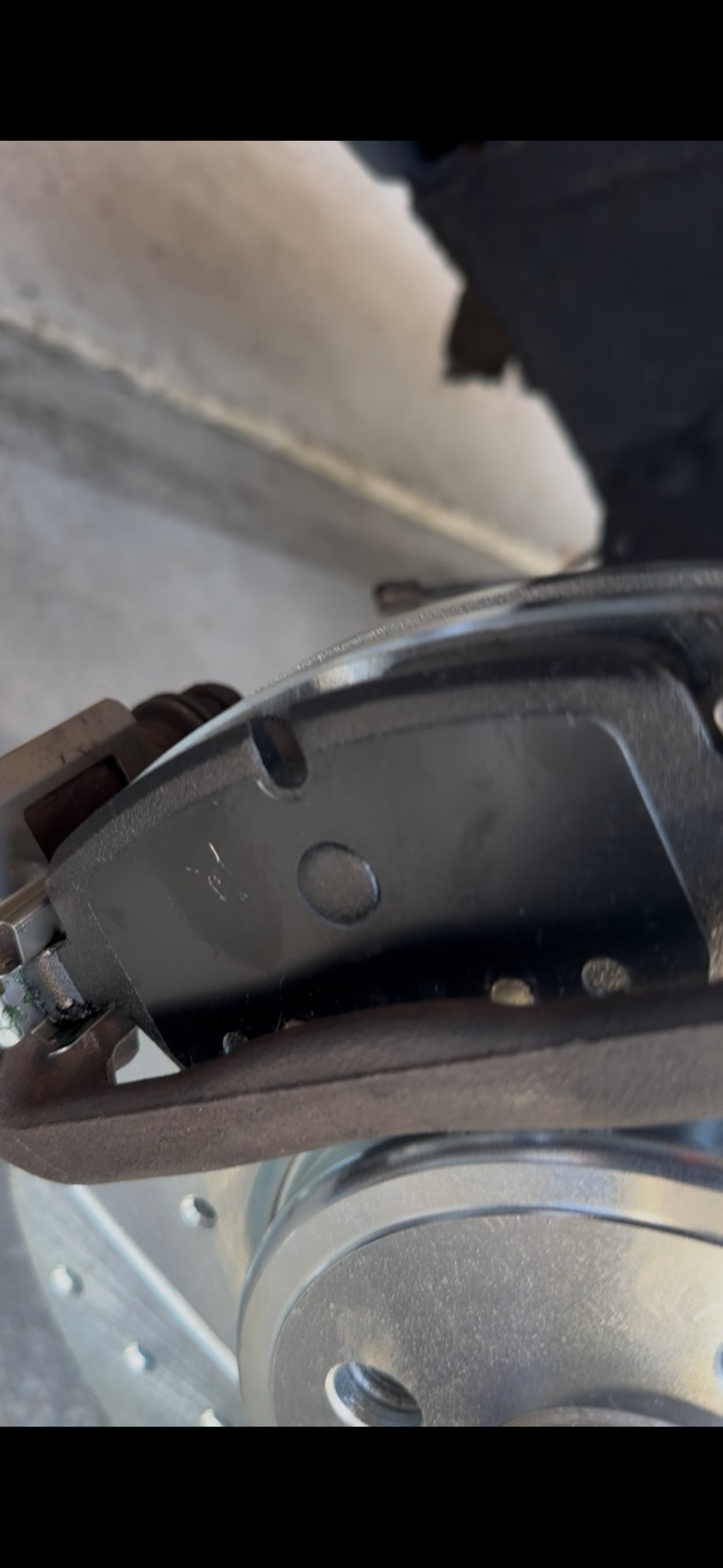 Close-up of a new front brake pad against the drilled and slotted rotor on a 2013 MINI Cooper Coupe S