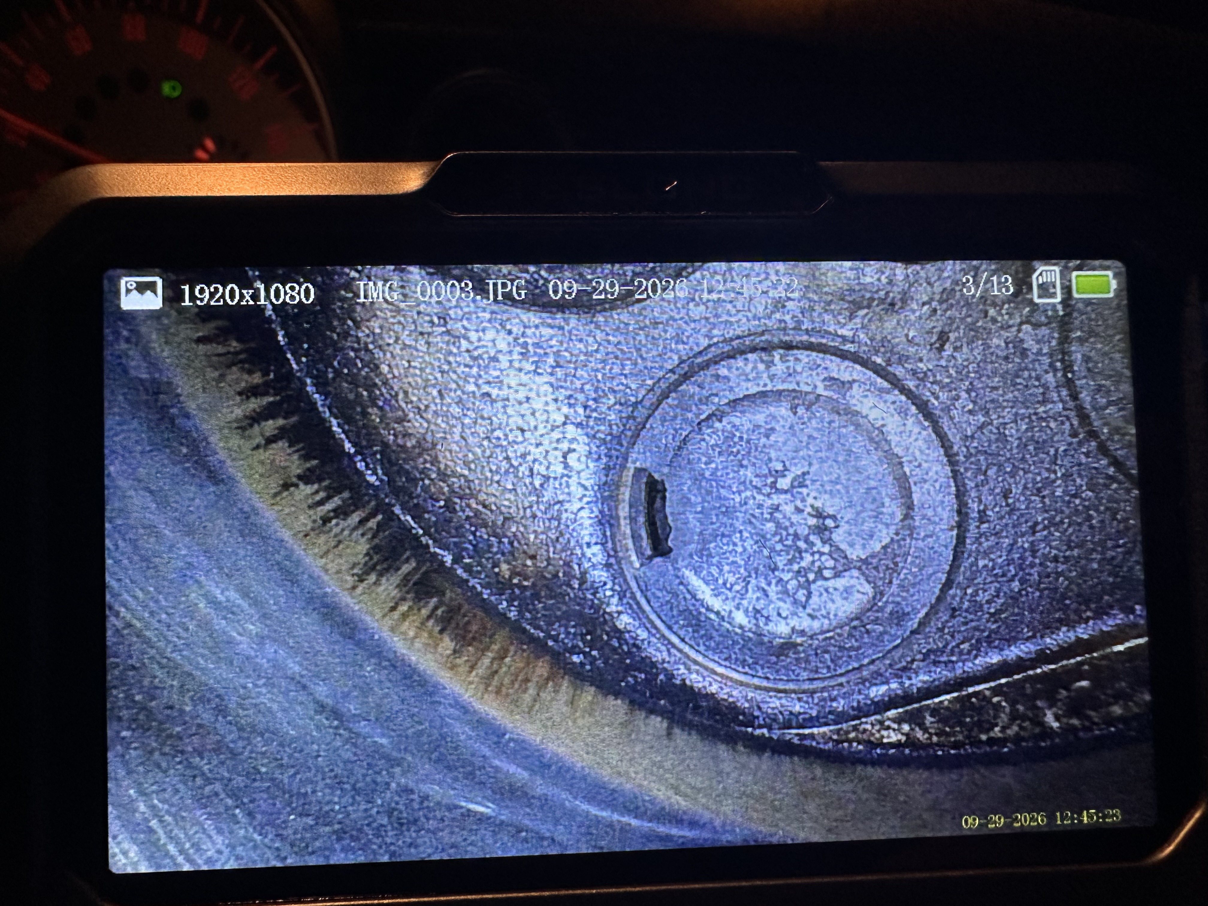 Borescope view through the cylinder 1 spark plug opening of the exhaust valve, with an irregular dark notch missing from the left edge of the valve head.