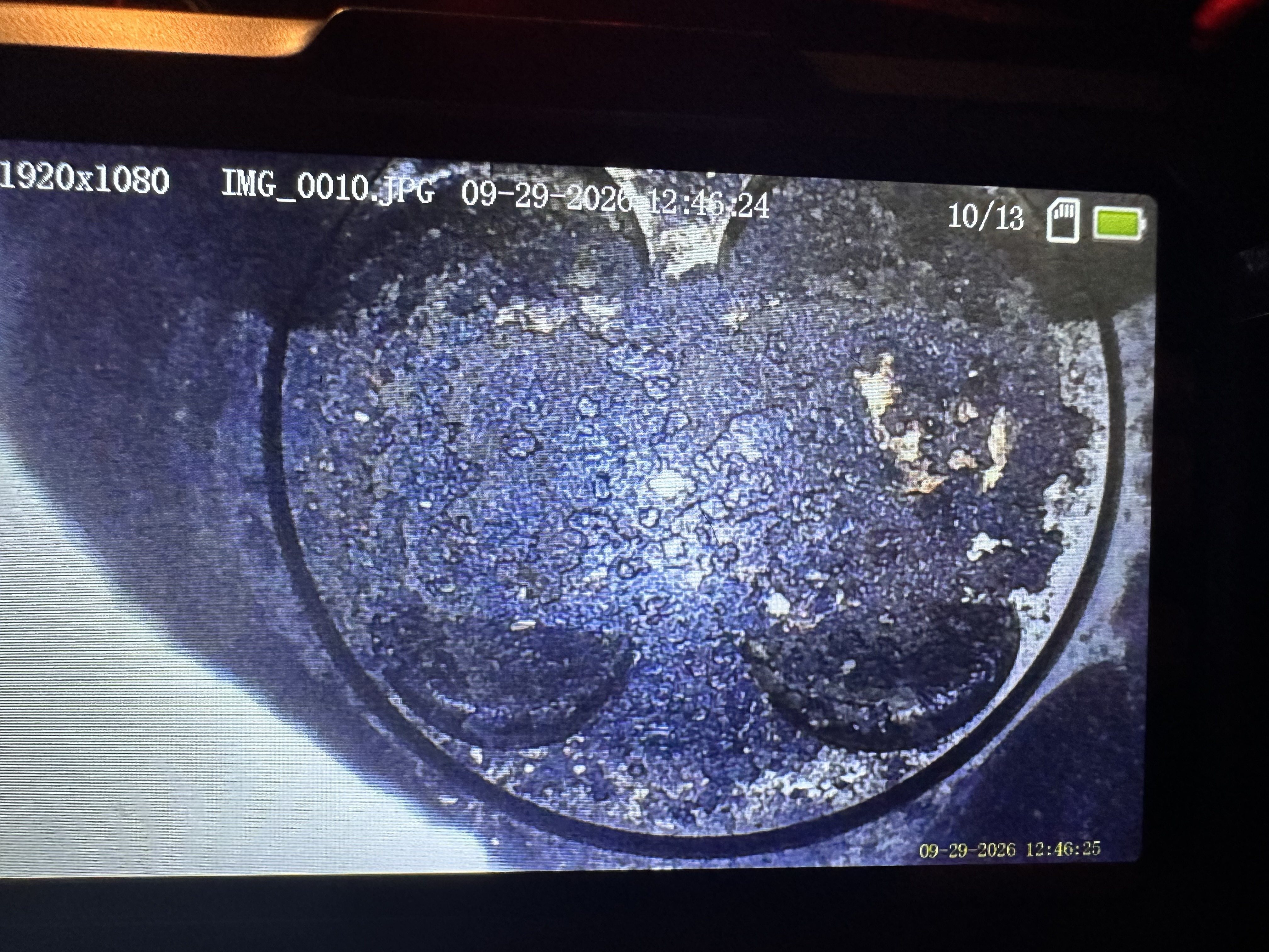Borescope view inside cylinder 1 showing carbon deposits with lighter flaked patches.