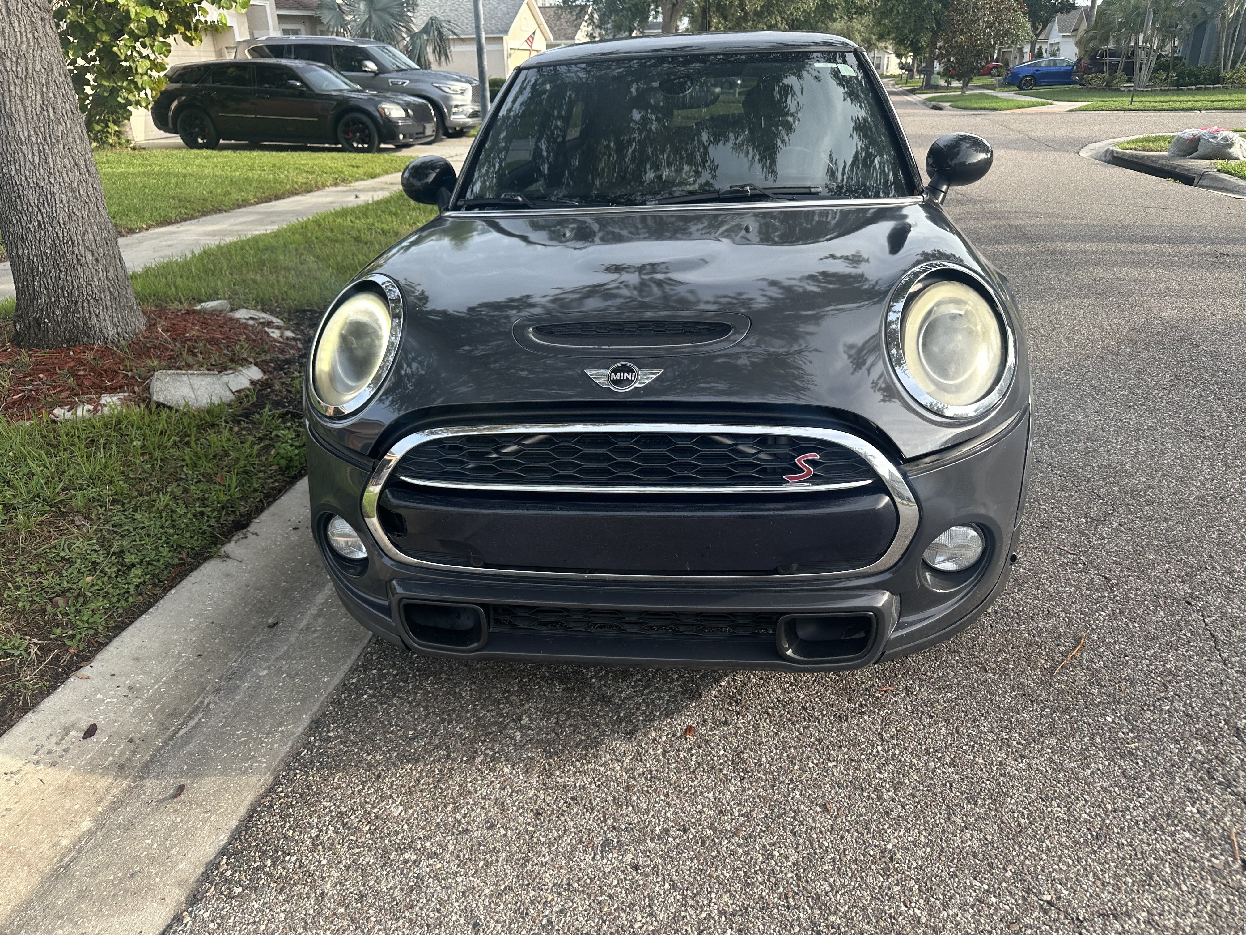 Front view of a grey three-door MINI Cooper S Hardtop parked at a kerb, with an S badge in the grille and hazed headlight lenses