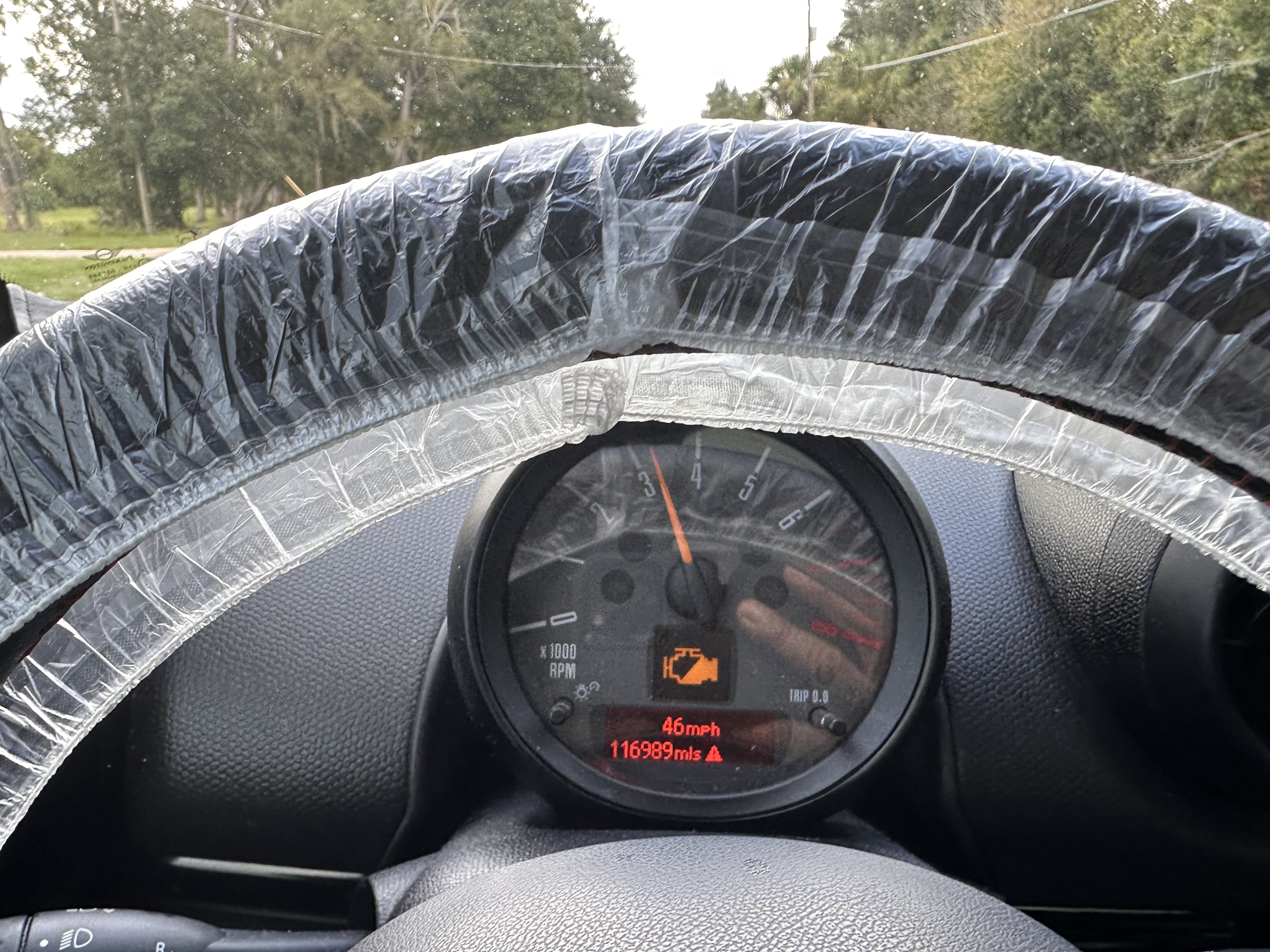 MINI rev counter showing an illuminated check-engine symbol with 46 mph and 116,989 miles displayed during a road test